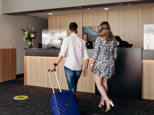 a man and a woman pulling a blue suitcase at Best Western Hobart in Hobart
