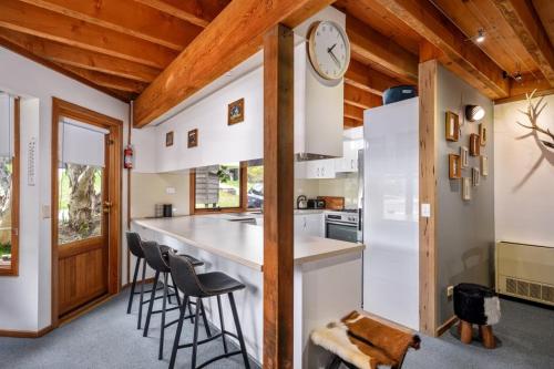 a kitchen with a bar with stools and a clock on the wall at Croajingalong in Dinner Plain