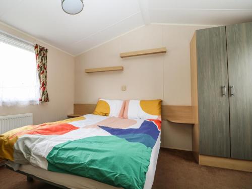 a bedroom with a bed with a colorful blanket at Solent Breezes, Caravan 108 in Southampton
