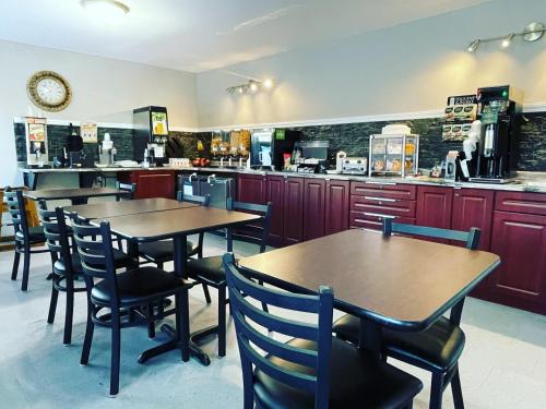ein Restaurant mit Tischen und Stühlen und einer Theke in der Unterkunft Moonlight Inn and Suites Sudbury in Sudbury