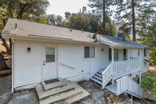 a small white house with a porch and stairs at Pine Place in Oakhurst