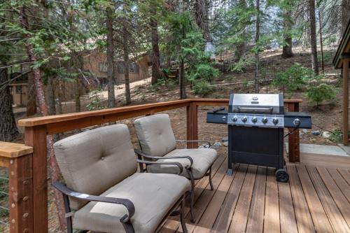 two chairs and a grill on a wooden deck at Yosemite Silvertip Lodge in Fish Camp