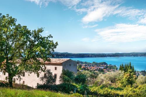 una vecchia casa su una collina con vista sull'acqua di Prati Palai a Bardolino