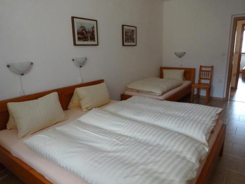 a bedroom with a large white bed and two chairs at Hostinec u Janatů s ubytováním in Čestín