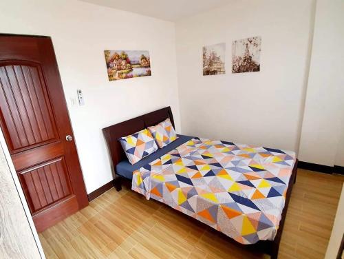 a bedroom with a bed with a colorful comforter at Kaitleen Home Stay Door 1 in Tacloban