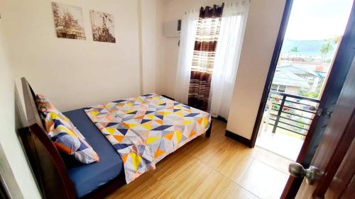 a small bedroom with a bed and a balcony at Kaitleen Home Stay Door 1 in Tacloban