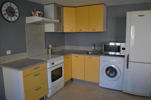 uma cozinha com armários amarelos e uma máquina de lavar roupa em L'Araucaria em Pontault-Combault