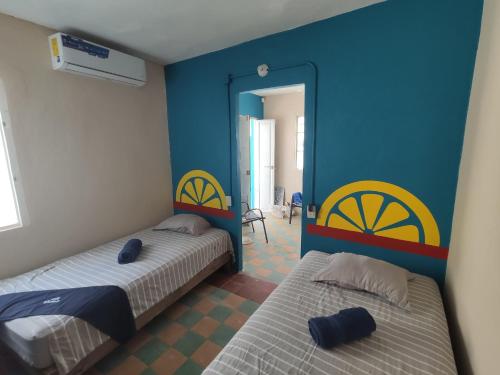 2 Betten in einem Zimmer mit blauen und gelben Wänden in der Unterkunft Chuchumbé Hotel & Hostal in Veracruz