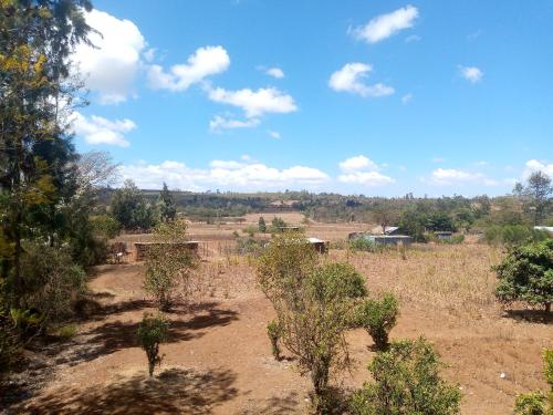 a field with trees and houses in the distance at Sipili Village Residence in Nyahururu