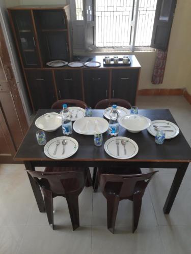 a dining room table with plates and glasses on it at Jungle View Home Stay in Dogadda