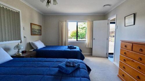 a bedroom with two blue beds and a window at Almost Country in Taupo