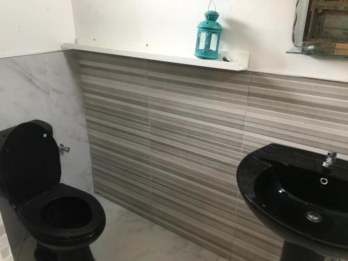 a bathroom with a black toilet and a sink at White Barn Chalet in Ragama