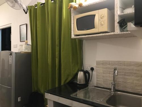 a kitchen with green curtains and a sink and a microwave at White Barn Chalet in Ragama