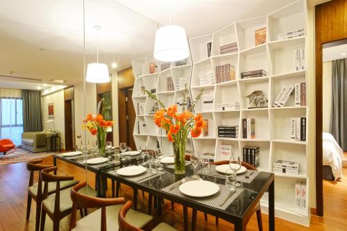 a dining room with a table with vases of flowers at Modena By Fraser New District Wuxi in Wuxi