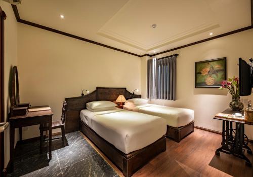 a hotel room with two beds and a desk at Amanaki Saigon Boutique Hotel in Ho Chi Minh City