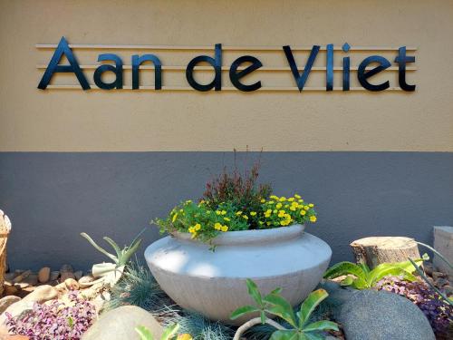 a sign on a building with a pot of flowers at Aan De Vliet Holiday Resort in Hazyview