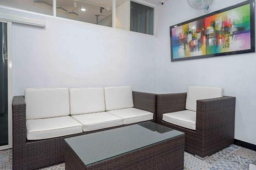 a living room with two white chairs and a table at RedDoorz Plus near Patung Kuda Undip in Jatingaleh