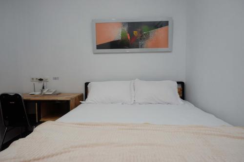 a bedroom with a bed with a desk and a picture on the wall at RedDoorz Plus near Patung Kuda Undip in Jatingaleh