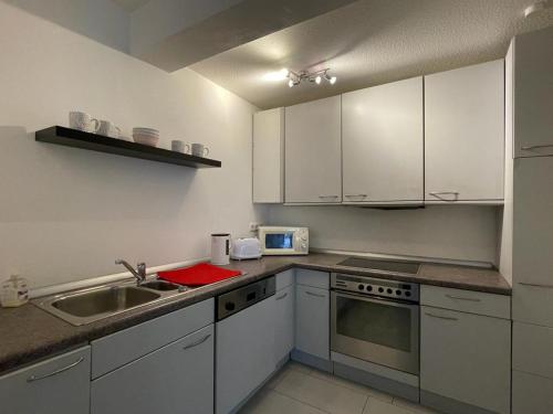 eine Küche mit weißen Schränken und einem Waschbecken in der Unterkunft Modernes Appartement in Gladbeck