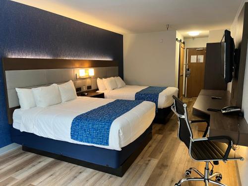 two beds in a hotel room with a desk and a chair at SureStay Plus Hotel by Best Western Mammoth Lakes in Mammoth Lakes