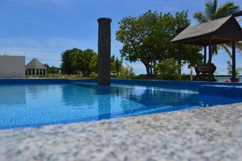 a blue swimming pool with an umbrella and trees at Lander's Bay Resort in Lautoka