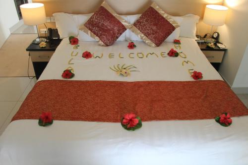 a bed with red flowers on it with the words welcome at Lander's Bay Resort in Lautoka