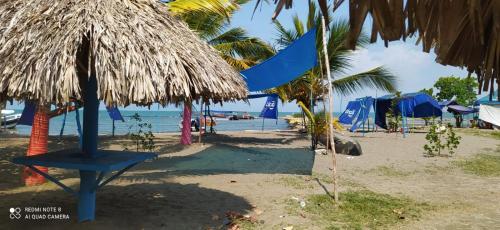 a beach with some blue umbrellas and the ocean at HOSTAL COVEÑAS INN in Coveñas