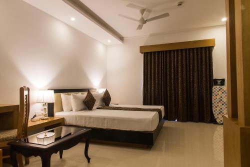 a bedroom with a bed and a table and a window at The Hotel Canoe in Kannur
