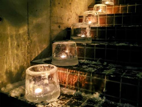 a group of glasses with lights on a wall at Pension Gooseberry in Furano