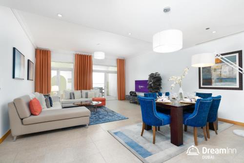 a living room with a table and blue chairs at Dream Inn - Shoreline Palm Jumeirah in Dubai