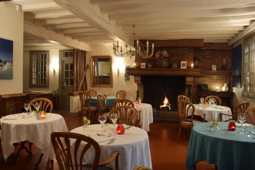 a dining room with tables and chairs and a fireplace at Le Relais Des Dalles in Sassetot-le-Mauconduit