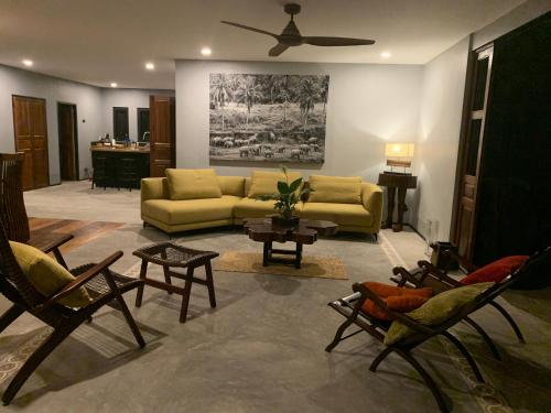 a living room with a yellow couch and chairs at I love phants Lodge in Ban Huai Thawai