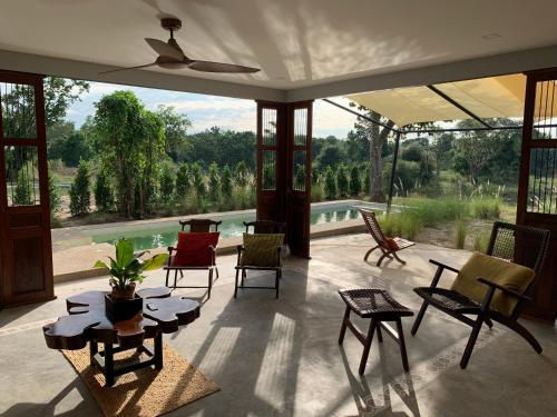 a living room with chairs and tables and a large window at I love phants Lodge in Ban Huai Thawai