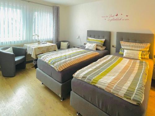 a bedroom with two beds and a chair at Landgasthof Zum Jossatal in Bad Soden-Salmünster