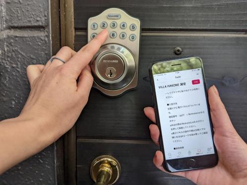 a person holding a cell phone in front of a door at VILLA HAKONE湖空 in Hakone