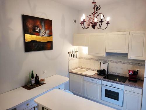 una cocina con armarios blancos y una pintura en la pared en St Nectaire- Appartement Terrasse Privée- 4 personnes en Saint-Nectaire