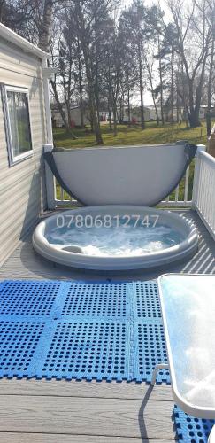 a bath tub sitting on a deck next to a pool at J S RETREATS @ TATTERSHALL LAKES in Tattershall