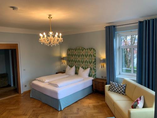 a bedroom with a bed and a chandelier and a couch at Hotel Kolbergarten in Bad Tölz