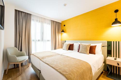 een slaapkamer met een groot bed en een gele muur bij atLumbreras16 in Sevilla