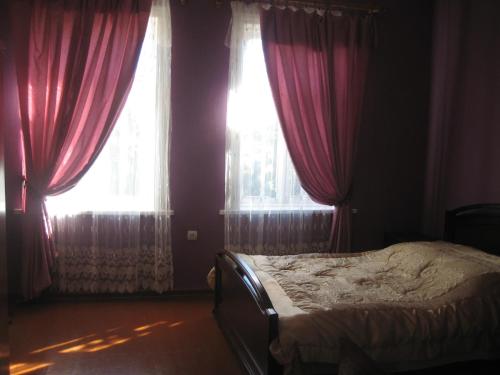 a bedroom with a bed with red curtains and a window at Guesthouse Gegi in Kutaisi
