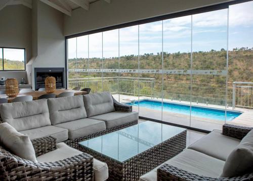 a living room with a couch and a swimming pool at Elements Sunrise Bush Lodge in Bela-Bela