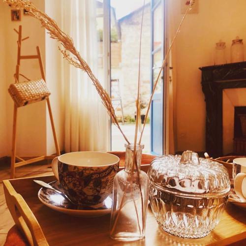 - une table en bois avec un vase et une tasse dans l'établissement Hôtes de Maïa Chambre d'hôtes chez l'habitant, à Moret-sur-Loing