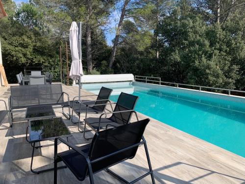 un patio avec une table et des chaises à côté d'une piscine dans l'établissement Magnifique Villa classée 4* meublé de tourisme, à Flassans-sur-Issole