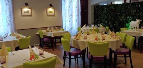 a restaurant with white tables and green chairs at Hôtel de Bourgogne in La Clayette