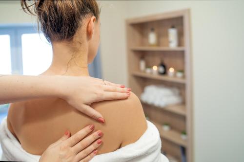 a woman is massaging the back of her stomach at Hotel Smrž in Sepekov