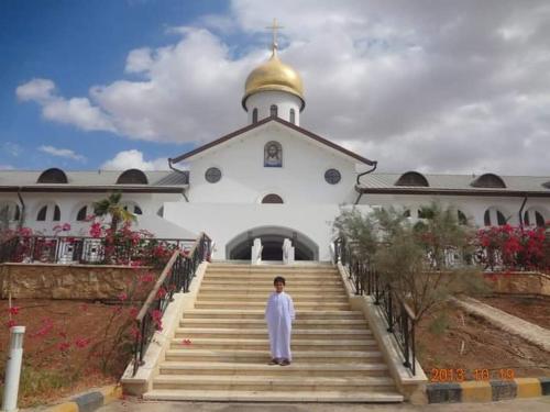a person standing on stairs in front of a church at Aitch Boutique Hotel - an LIH Hotel in Madaba