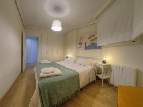 1 dormitorio con 1 cama con manta verde en Vistamar. Primera línea. Bahía de Santoña, en Santoña