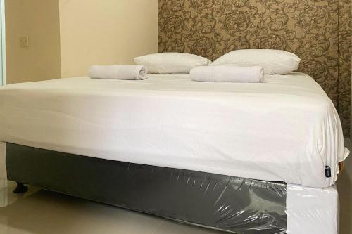 a large bed with white sheets and pillows on it at CK Homestay Syariah near Lippo Plaza Jambi Mitra RedDoorz in Paalmerah