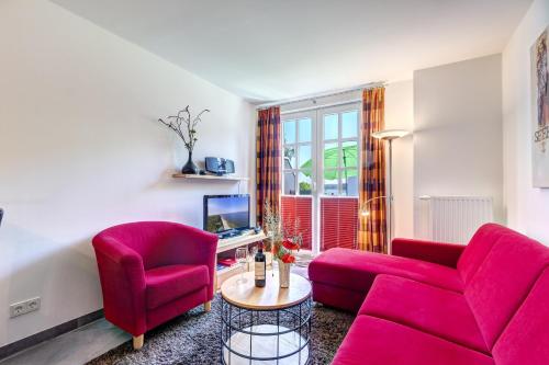 ein Wohnzimmer mit einem roten Sofa und 2 Stühlen in der Unterkunft Residenz am Balmer See - BS 48 mit Wellnessbereich in Balm