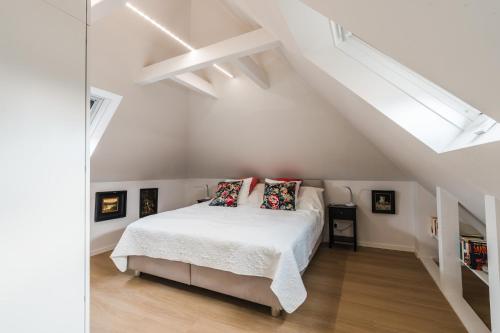 a white bedroom with a bed in a attic at Appartement HIMMEL & Höllerl in Fürstenfeld